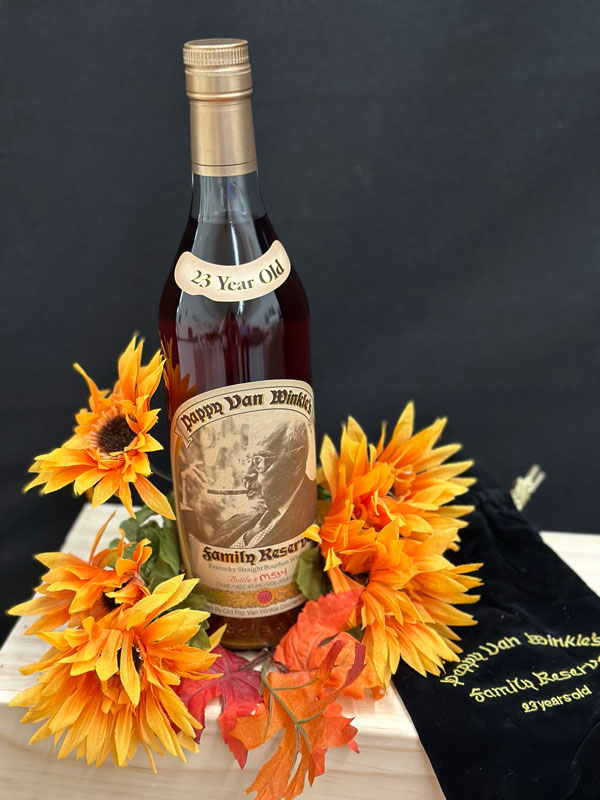 Pappy Van Winkle 23 year old bourbon bottle surrounded by flowers.