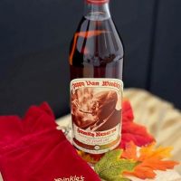 Pappy Van Winkle 20 year old bourbon bottle surrounded by flowers.