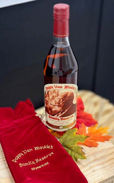 Pappy Van Winkle 20 year old bourbon bottle surrounded by flowers.